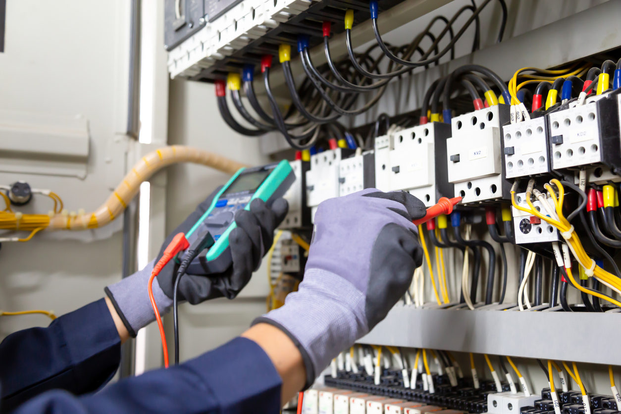 Electrician engineer tests electrical installations and wires on relay protection system. Adjustment of scheme of automation and control of electrical equipment.